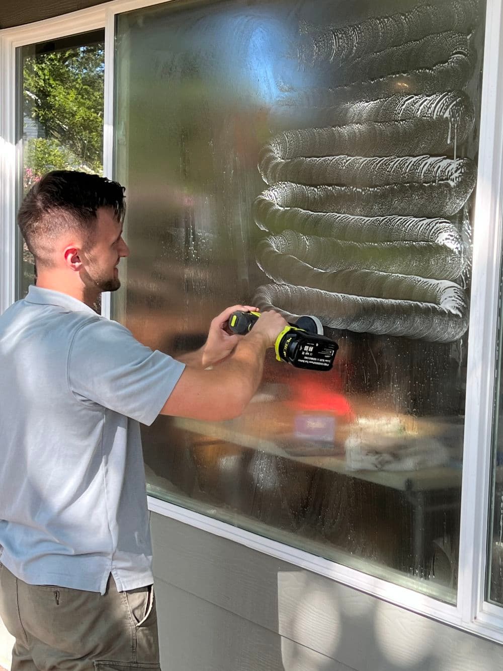 Man cleaning a window with a power squeegee, demonstrating efficient window maintenance techniques.