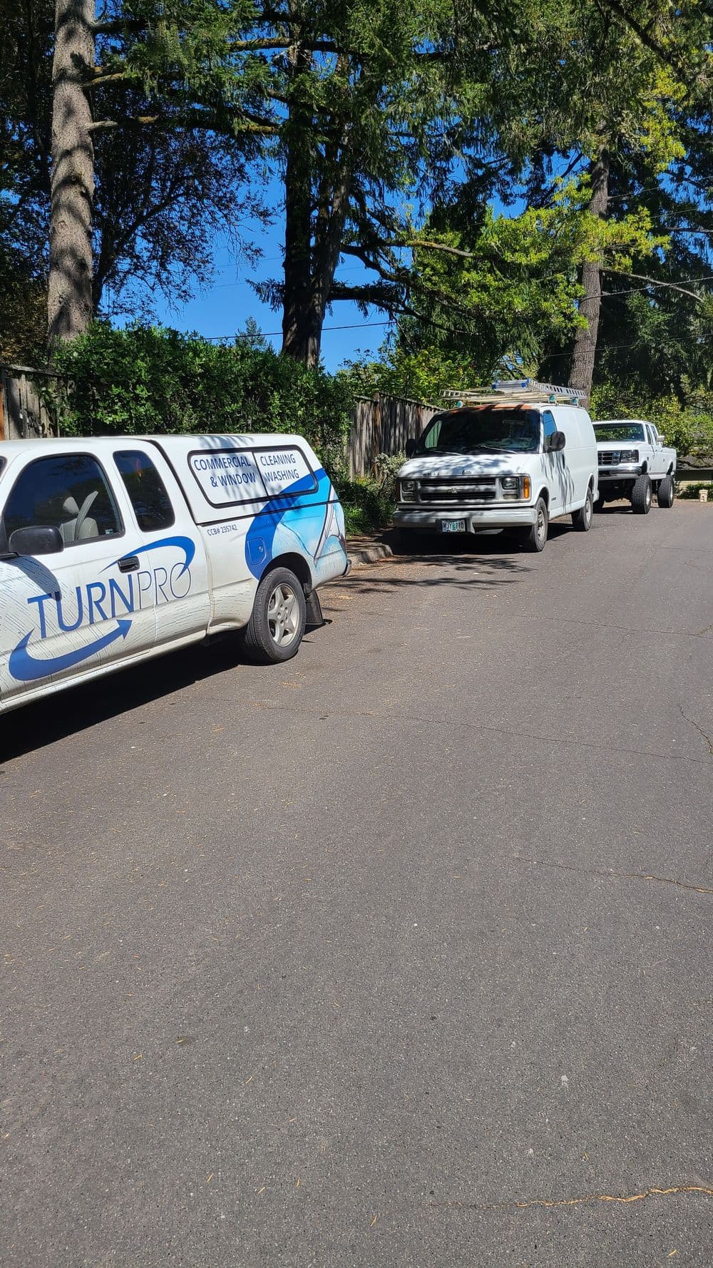 TurnPro service vehicle parked on a residential street alongside two other utility vans.